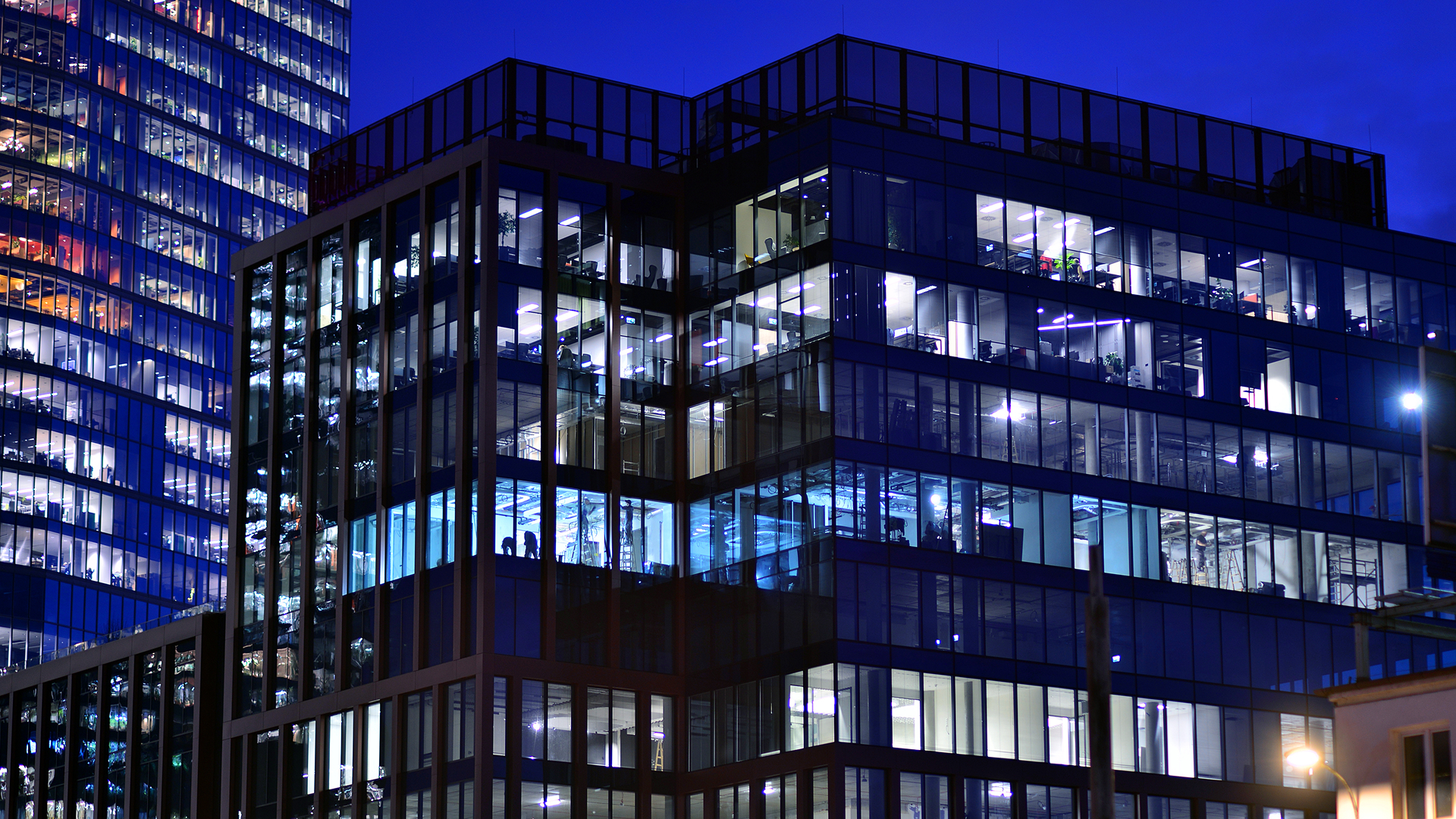 Building energy simulation and occupancy shown by a modern office building at dusk with a scattered pattern of lit and dark floors